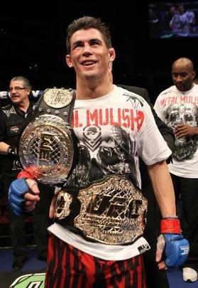 Dominick Cruz, em janeiro de 2014 - Cruz foi destituído do título ao se lesionar repetidamente em uma sequência de 2 anos. Renan Barão foi promovido à Campeão Incontestável dos Galos