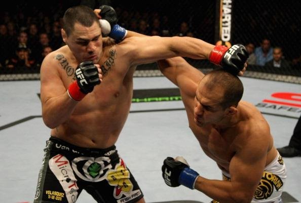 Na primeira defesa, o primeiro revs. Velasquez, que ficou mais de um ano afastado, foi nocauteado rapidamente pelo brasileiro Junior Cigano