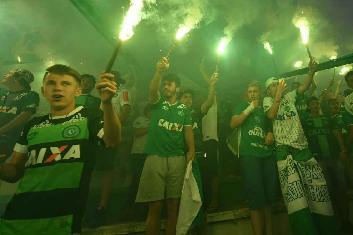 Foi na Arena ndio Cond que a Chapecoense deixou o 'anonimato' para ganhar os coraes de todos os brasileiros. Em seu estdio, o Verdo do Oeste mostrou toda sua valentia ao permanecer por trs anos seguidos na Srie A e, consequentemente, alcanar a deciso da Copa Sul-Americana. Pelo caminho ficaram gigantes como os argentinos Independiente e San Lorenzo e o colombiano Junior Barranquilla. Restava apenas o poderoso Atltico Nacional, melhor clube da atualidade na Amrica do Sul. Dentro de campo, a Chape no pde dar sequncia  sua bravura, pois acabou vitimada por um acidente areo que matou quase toda sua delegao nas proximidades de Medelln, na Colmbia. Mas, se depender do amor de uma multido, o clube renascer. A mesma Arena Cond que foi palco de trs acessos - da Srie D para a C, em 2009; da C para a B, em 2012; e da B para a A, em 2013 -  o local onde milhares de torcedores prestam as ltimas homenagens aos falecidos. Sempre, claro, com a esperana de que a agremiao se reerguer e dar continuidade ao belo trabalho recente. Vamos, vamos Chape!!! (CRDITO DAS IMAGENS: NELSON ALMEIDA/AFP)