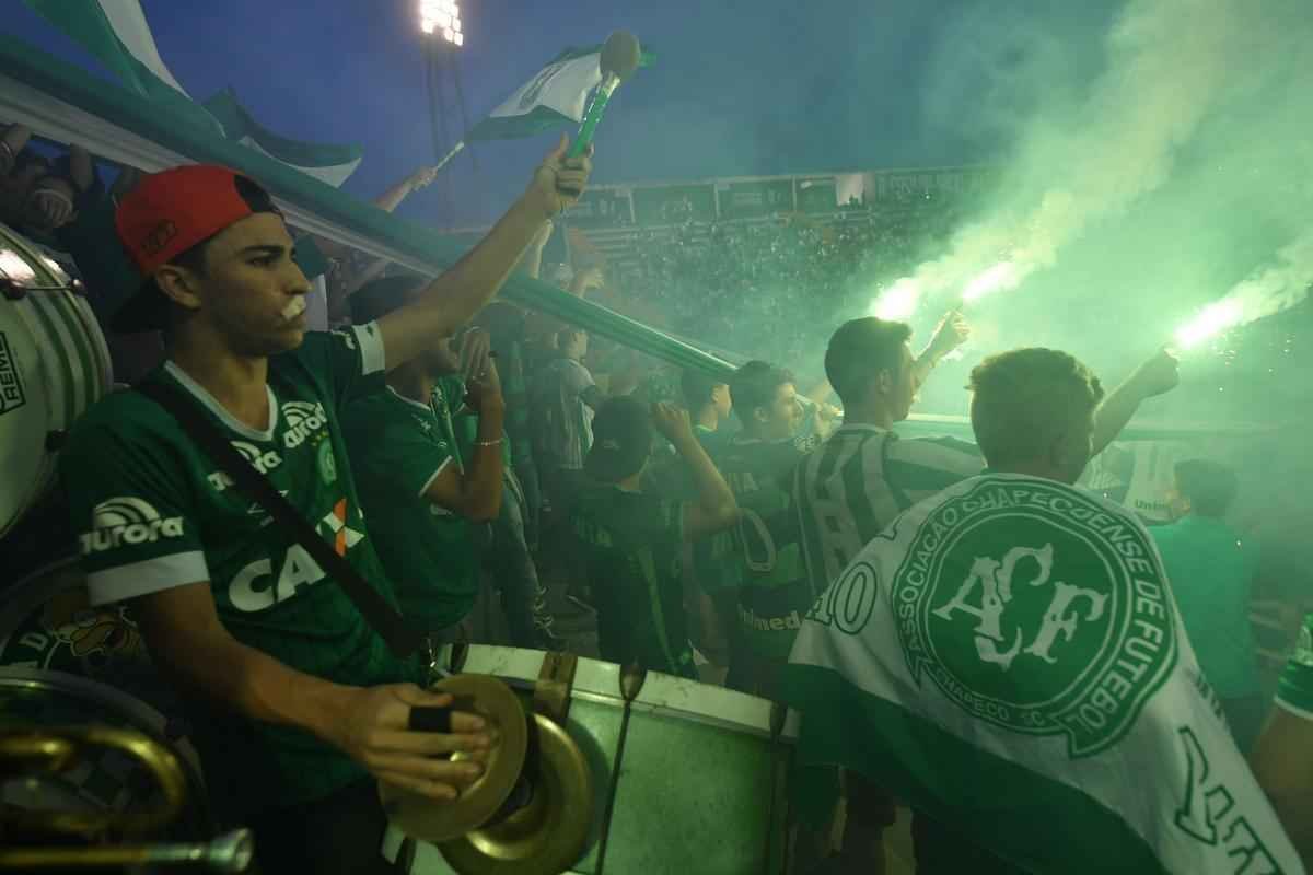 Foi na Arena ndio Cond que a Chapecoense deixou o 'anonimato' para ganhar os coraes de todos os brasileiros. Em seu estdio, o Verdo do Oeste mostrou toda sua valentia ao permanecer por trs anos seguidos na Srie A e, consequentemente, alcanar a deciso da Copa Sul-Americana. Pelo caminho ficaram gigantes como os argentinos Independiente e San Lorenzo e o colombiano Junior Barranquilla. Restava apenas o poderoso Atltico Nacional, melhor clube da atualidade na Amrica do Sul. Dentro de campo, a Chape no pde dar sequncia  sua bravura, pois acabou vitimada por um acidente areo que matou quase toda sua delegao nas proximidades de Medelln, na Colmbia. Mas, se depender do amor de uma multido, o clube renascer. A mesma Arena Cond que foi palco de trs acessos - da Srie D para a C, em 2009; da C para a B, em 2012; e da B para a A, em 2013 -  o local onde milhares de torcedores prestam as ltimas homenagens aos falecidos. Sempre, claro, com a esperana de que a agremiao se reerguer e dar continuidade ao belo trabalho recente. Vamos, vamos Chape!!! (CRDITO DAS IMAGENS: NELSON ALMEIDA/AFP)