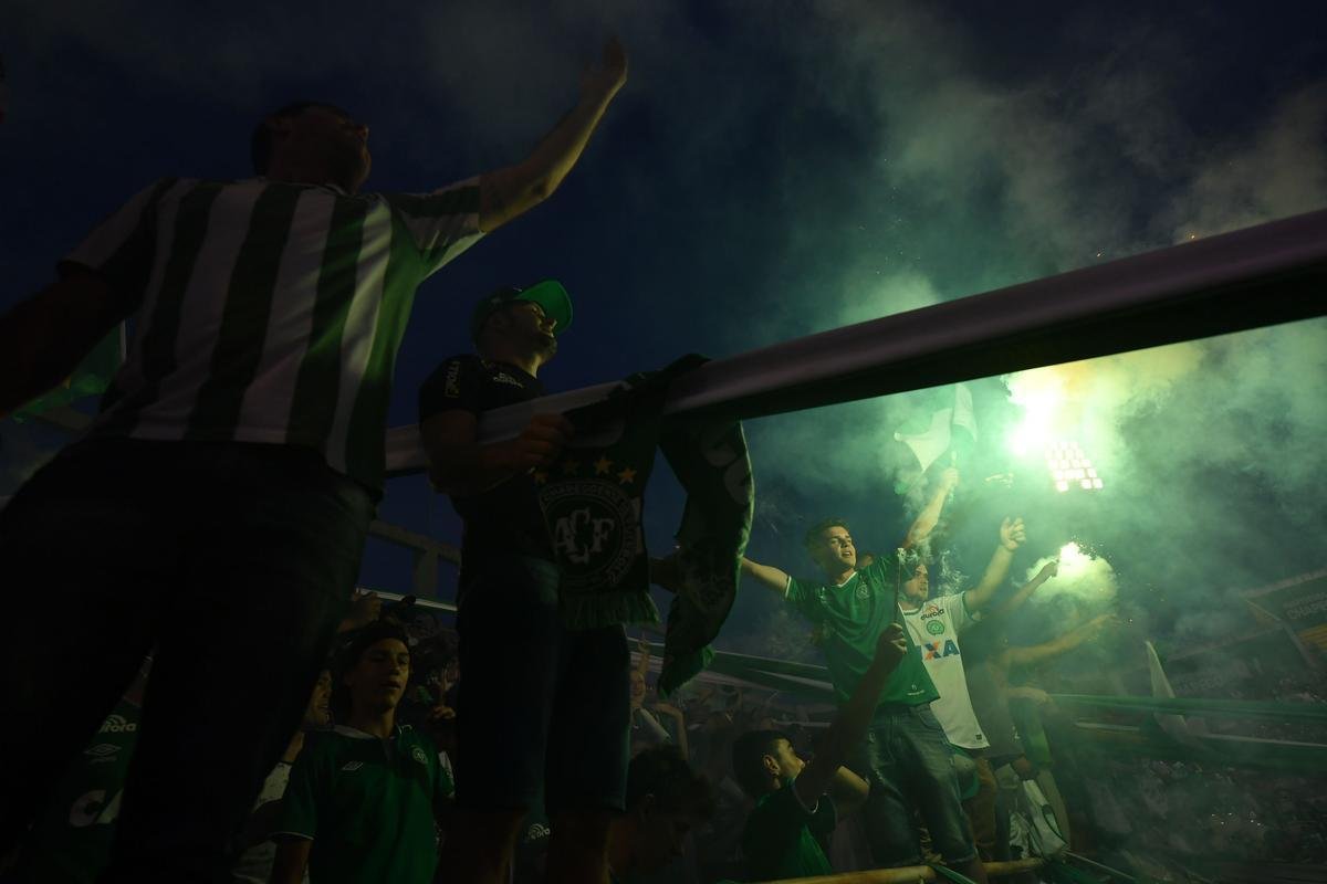 Foi na Arena ndio Cond que a Chapecoense deixou o 'anonimato' para ganhar os coraes de todos os brasileiros. Em seu estdio, o Verdo do Oeste mostrou toda sua valentia ao permanecer por trs anos seguidos na Srie A e, consequentemente, alcanar a deciso da Copa Sul-Americana. Pelo caminho ficaram gigantes como os argentinos Independiente e San Lorenzo e o colombiano Junior Barranquilla. Restava apenas o poderoso Atltico Nacional, melhor clube da atualidade na Amrica do Sul. Dentro de campo, a Chape no pde dar sequncia  sua bravura, pois acabou vitimada por um acidente areo que matou quase toda sua delegao nas proximidades de Medelln, na Colmbia. Mas, se depender do amor de uma multido, o clube renascer. A mesma Arena Cond que foi palco de trs acessos - da Srie D para a C, em 2009; da C para a B, em 2012; e da B para a A, em 2013 -  o local onde milhares de torcedores prestam as ltimas homenagens aos falecidos. Sempre, claro, com a esperana de que a agremiao se reerguer e dar continuidade ao belo trabalho recente. Vamos, vamos Chape!!! (CRDITO DAS IMAGENS: NELSON ALMEIDA/AFP)