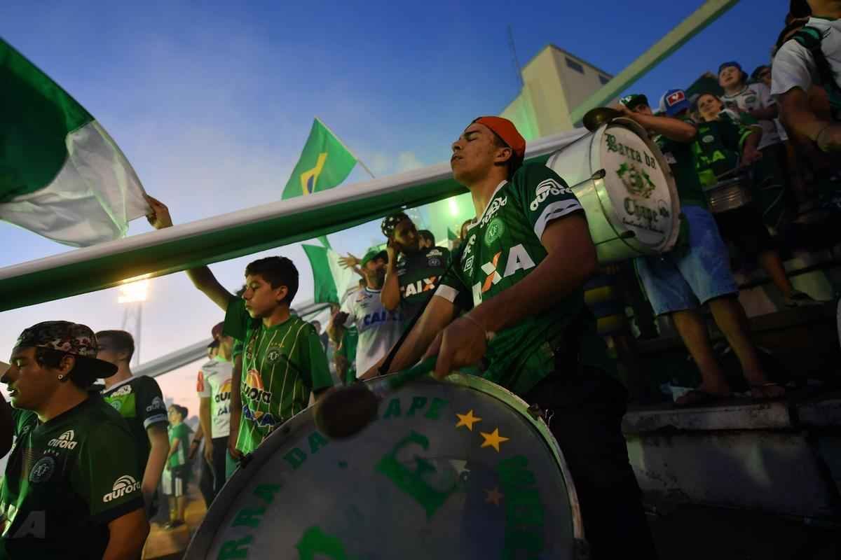 Foi na Arena ndio Cond que a Chapecoense deixou o 'anonimato' para ganhar os coraes de todos os brasileiros. Em seu estdio, o Verdo do Oeste mostrou toda sua valentia ao permanecer por trs anos seguidos na Srie A e, consequentemente, alcanar a deciso da Copa Sul-Americana. Pelo caminho ficaram gigantes como os argentinos Independiente e San Lorenzo e o colombiano Junior Barranquilla. Restava apenas o poderoso Atltico Nacional, melhor clube da atualidade na Amrica do Sul. Dentro de campo, a Chape no pde dar sequncia  sua bravura, pois acabou vitimada por um acidente areo que matou quase toda sua delegao nas proximidades de Medelln, na Colmbia. Mas, se depender do amor de uma multido, o clube renascer. A mesma Arena Cond que foi palco de trs acessos - da Srie D para a C, em 2009; da C para a B, em 2012; e da B para a A, em 2013 -  o local onde milhares de torcedores prestam as ltimas homenagens aos falecidos. Sempre, claro, com a esperana de que a agremiao se reerguer e dar continuidade ao belo trabalho recente. Vamos, vamos Chape!!! (CRDITO DAS IMAGENS: NELSON ALMEIDA/AFP)
