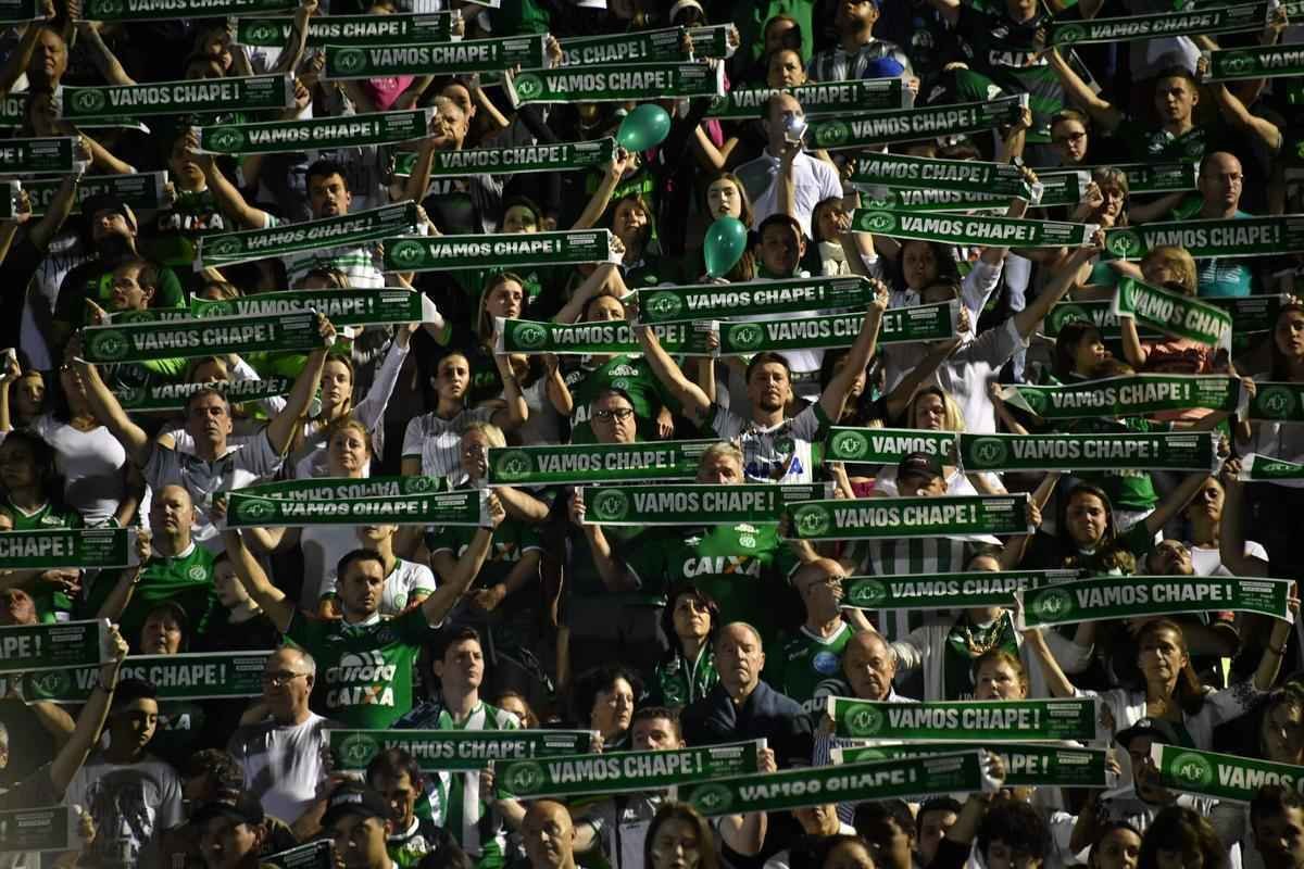Foi na Arena ndio Cond que a Chapecoense deixou o 'anonimato' para ganhar os coraes de todos os brasileiros. Em seu estdio, o Verdo do Oeste mostrou toda sua valentia ao permanecer por trs anos seguidos na Srie A e, consequentemente, alcanar a deciso da Copa Sul-Americana. Pelo caminho ficaram gigantes como os argentinos Independiente e San Lorenzo e o colombiano Junior Barranquilla. Restava apenas o poderoso Atltico Nacional, melhor clube da atualidade na Amrica do Sul. Dentro de campo, a Chape no pde dar sequncia  sua bravura, pois acabou vitimada por um acidente areo que matou quase toda sua delegao nas proximidades de Medelln, na Colmbia. Mas, se depender do amor de uma multido, o clube renascer. A mesma Arena Cond que foi palco de trs acessos - da Srie D para a C, em 2009; da C para a B, em 2012; e da B para a A, em 2013 -  o local onde milhares de torcedores prestam as ltimas homenagens aos falecidos. Sempre, claro, com a esperana de que a agremiao se reerguer e dar continuidade ao belo trabalho recente. Vamos, vamos Chape!!! (CRDITO DAS IMAGENS: NELSON ALMEIDA/AFP)