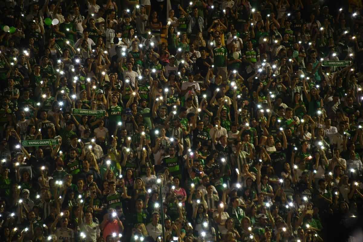 Foi na Arena ndio Cond que a Chapecoense deixou o 'anonimato' para ganhar os coraes de todos os brasileiros. Em seu estdio, o Verdo do Oeste mostrou toda sua valentia ao permanecer por trs anos seguidos na Srie A e, consequentemente, alcanar a deciso da Copa Sul-Americana. Pelo caminho ficaram gigantes como os argentinos Independiente e San Lorenzo e o colombiano Junior Barranquilla. Restava apenas o poderoso Atltico Nacional, melhor clube da atualidade na Amrica do Sul. Dentro de campo, a Chape no pde dar sequncia  sua bravura, pois acabou vitimada por um acidente areo que matou quase toda sua delegao nas proximidades de Medelln, na Colmbia. Mas, se depender do amor de uma multido, o clube renascer. A mesma Arena Cond que foi palco de trs acessos - da Srie D para a C, em 2009; da C para a B, em 2012; e da B para a A, em 2013 -  o local onde milhares de torcedores prestam as ltimas homenagens aos falecidos. Sempre, claro, com a esperana de que a agremiao se reerguer e dar continuidade ao belo trabalho recente. Vamos, vamos Chape!!! (CRDITO DAS IMAGENS: NELSON ALMEIDA/AFP)