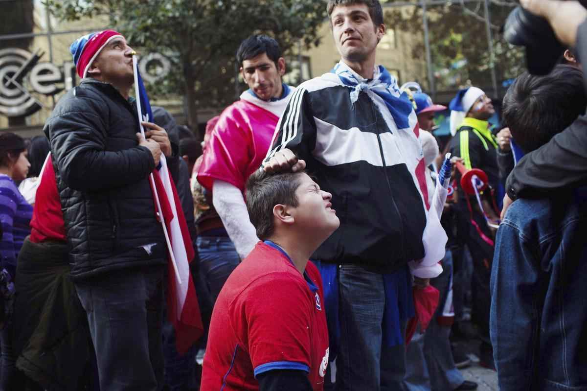 Nas ruas de Santiago, capital do Chile, torcedores da 'Roja' assistem  eliminao diante do Brasil na Copa do Mundo