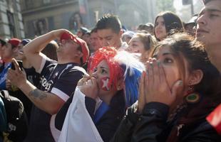 Nas ruas de Santiago, capital do Chile, torcedores da 'Roja' assistem  eliminao diante do Brasil na Copa do Mundo
