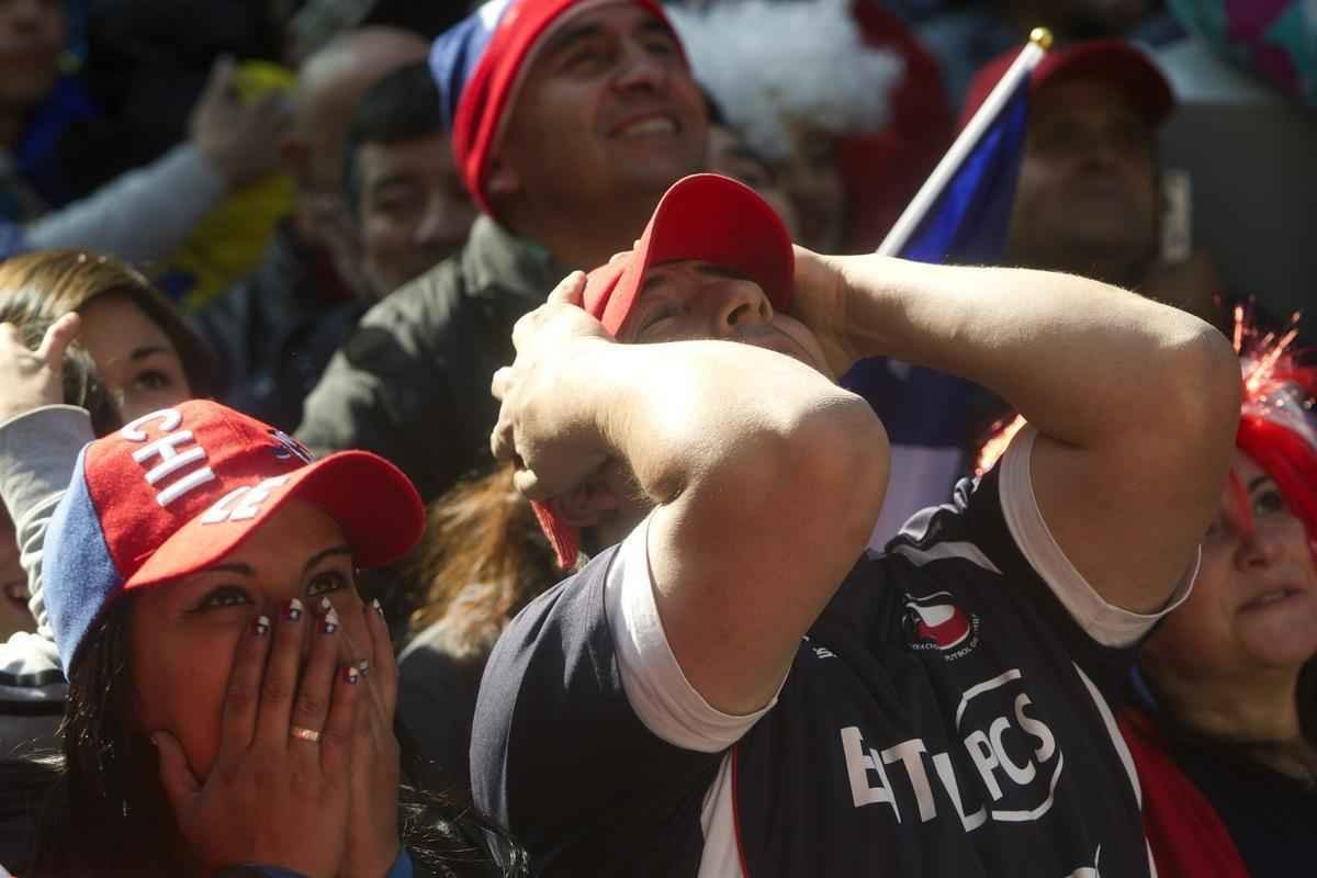 Nas ruas de Santiago, capital do Chile, torcedores da 'Roja' assistem  eliminao diante do Brasil na Copa do Mundo