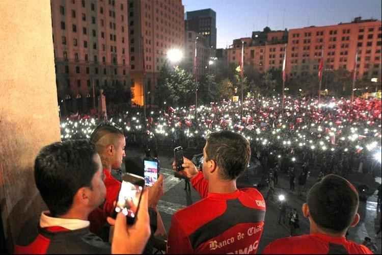 Multido e presidente receberam Seleo Chilena no Palcio de La Moneda, em Santiago. Populao reconheceu a boa campanha da equipe na Copa do Mundo, da qual foi eliminada pelo Brasil, nos pnaltis, por 3 a 2 (empate em 1 a 1 no tempo normal).
