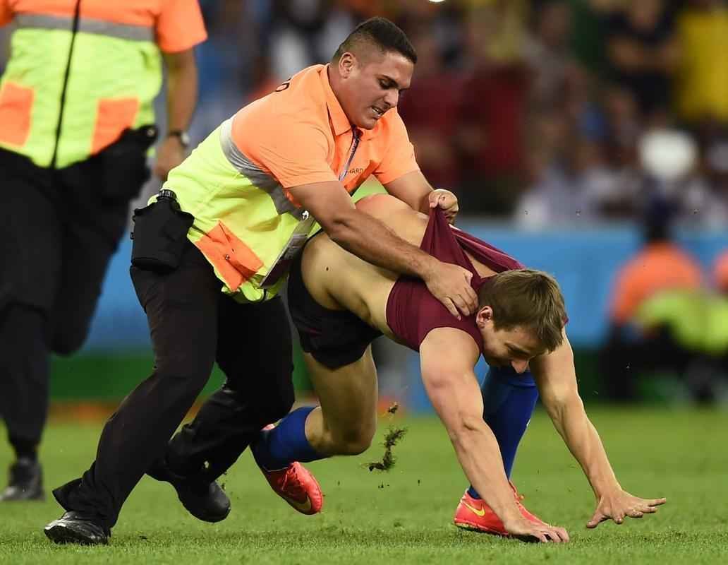 Com dizeres 'brincalho por natureza' na barriga, torcedor invade gramado do Maracan durante a final da Copa do Mundo, entre Alemanha e Argentina, e d trabalho  segurana at ser retirado 