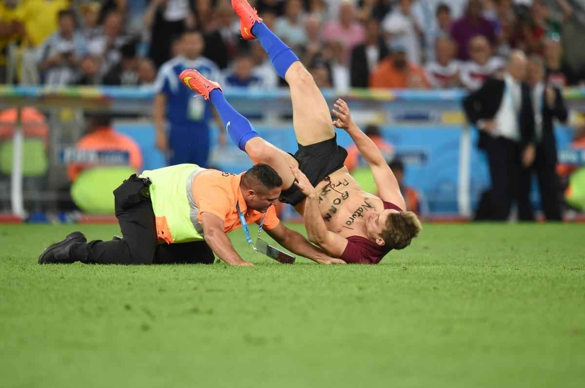 Com dizeres 'brincalho por natureza' na barriga, torcedor invade gramado do Maracan durante a final da Copa do Mundo, entre Alemanha e Argentina, e d trabalho  segurana at ser retirado 